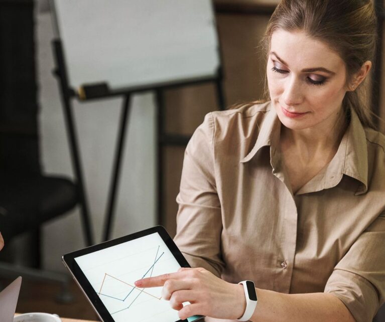 Cuatro mujeres en una reunión analizan datos en una tablet, mostrando gráficos y discutiendo estrategias.